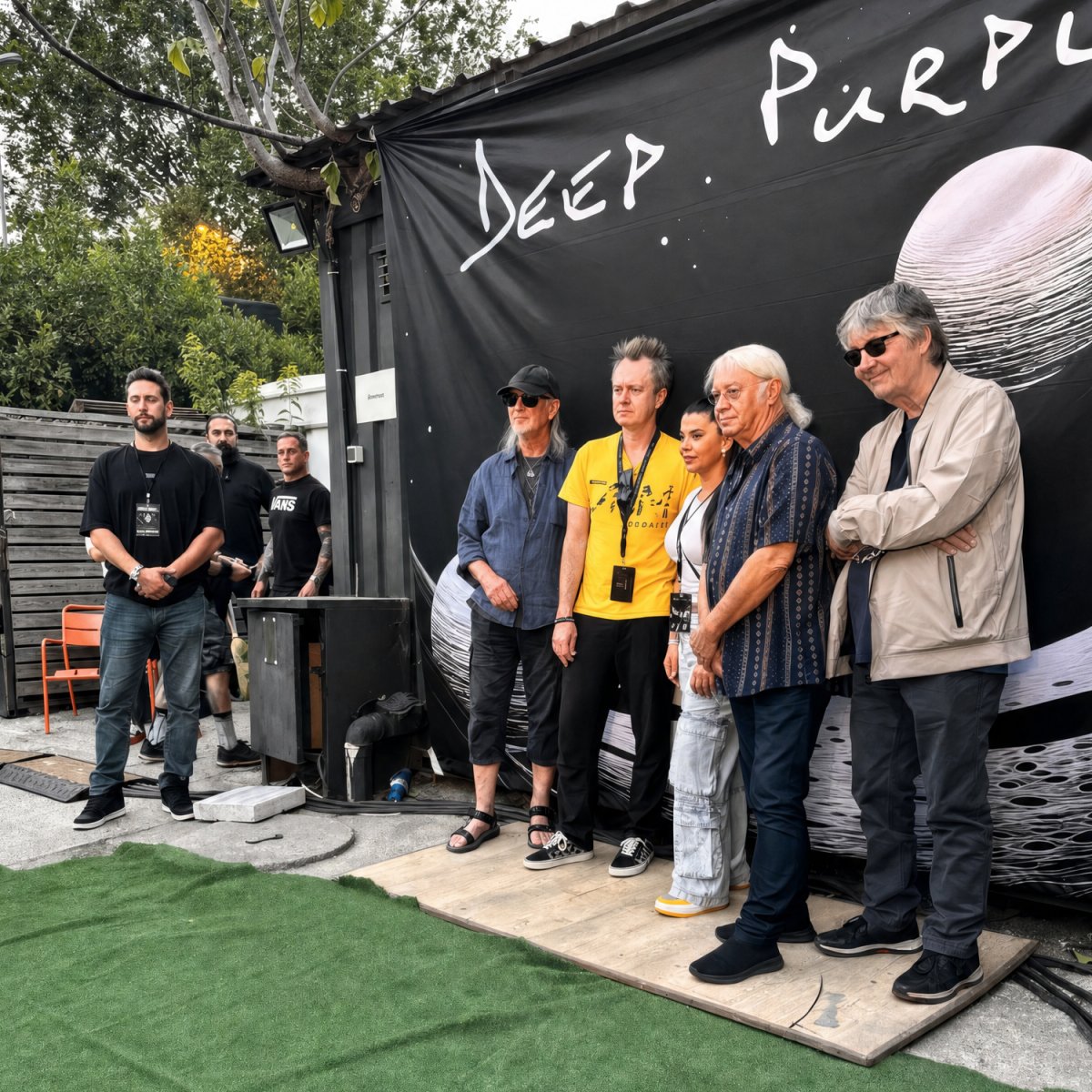 Deep Purple, sahne arkasında grup afişinin önünde, Agun Security ile