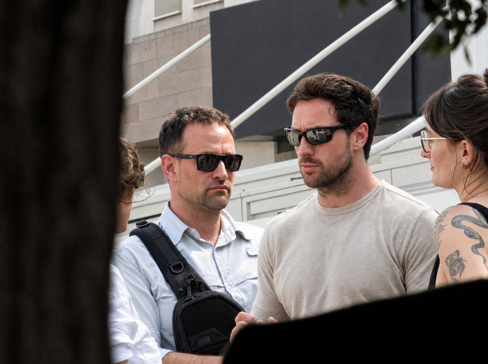 Aaron Taylor-Johnson, şehir sokağında güneş gözlüklü bir Agun Security görevlisinin yanında